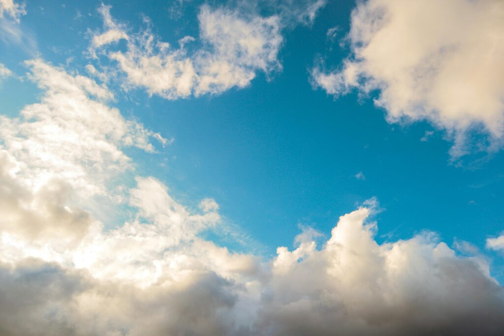 A bright blue sky adorned with fluffy white clouds, creating a peaceful and serene atmosphere.